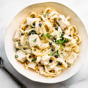 Fettuccine Alfredo with chicken in a white bowl topped with cheese