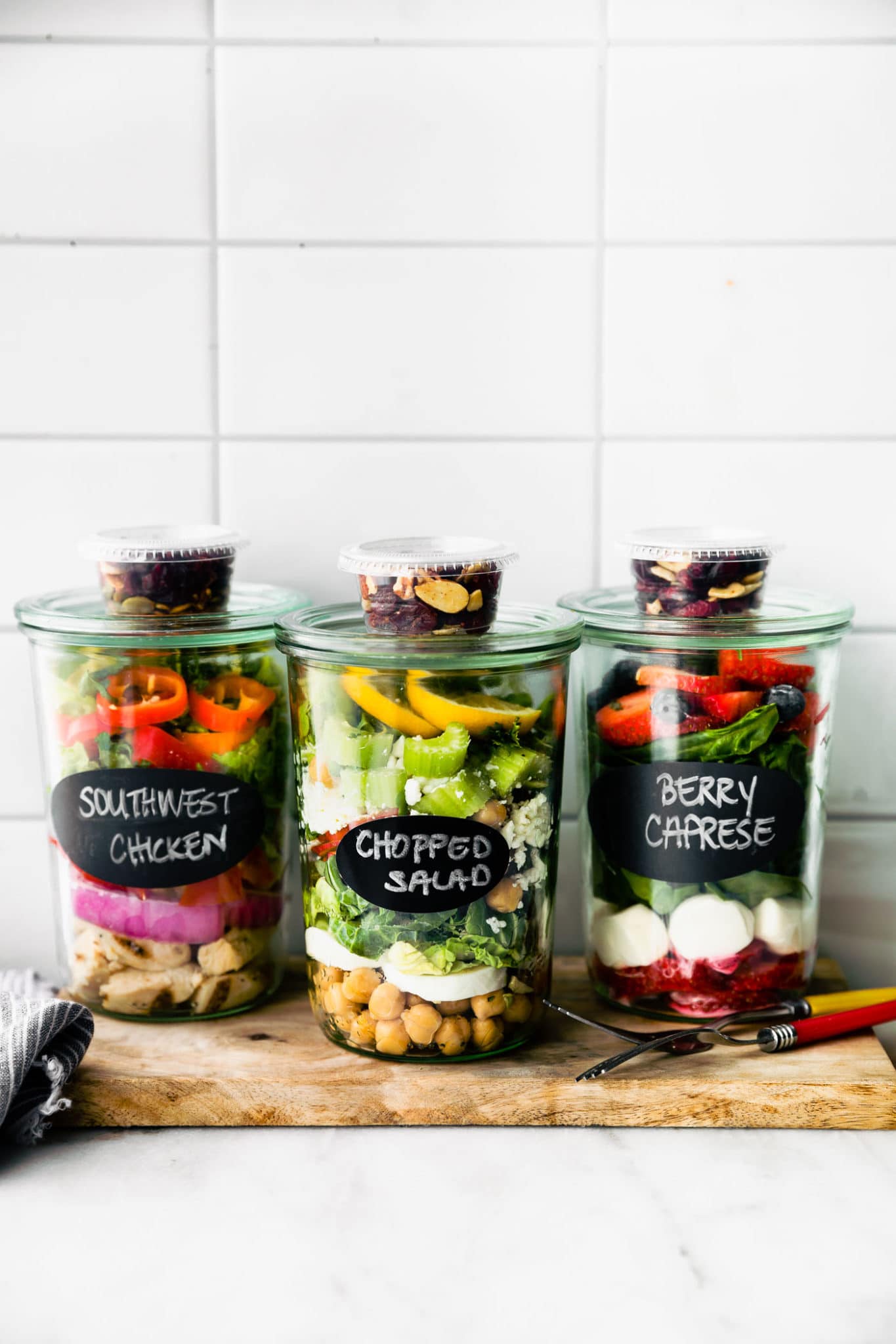 Close up image of three mason jar salads with mariani salad toppers.