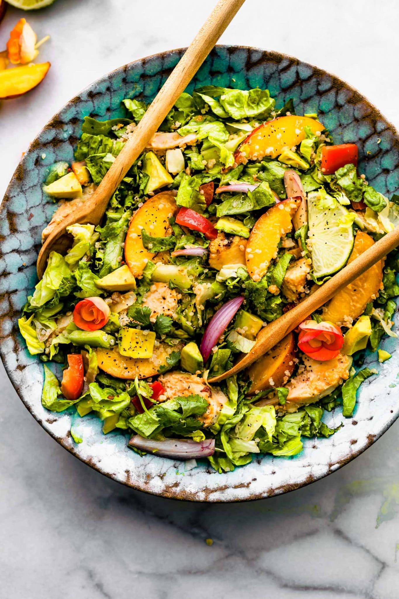 Overhead image of chipotle chicken salad bowl with peaches and two serving spoons