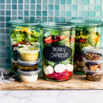 A photo of 3 mason jar salads sitting on a counter.