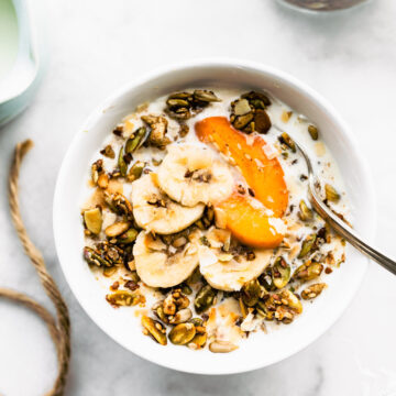 pumpkin spice granola served as cereal in a bowl with fresh fruit and a spoon