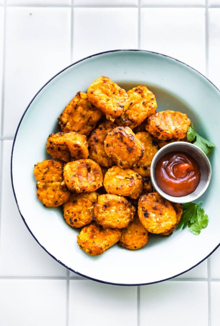 sweet potato tots in a white bowl with ketchup on the side