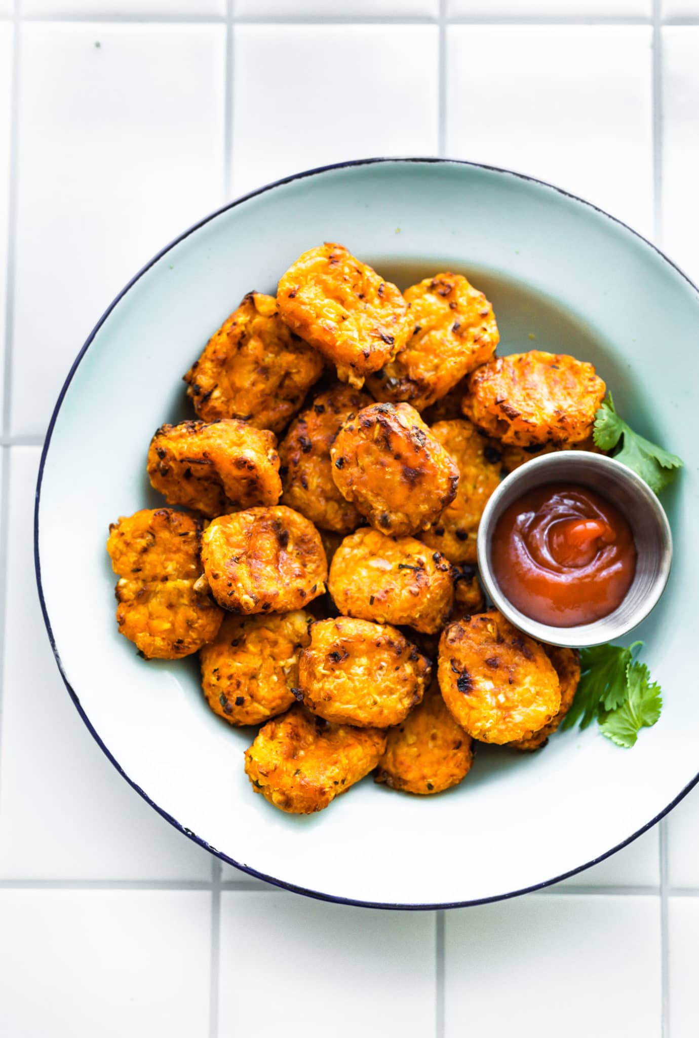 sweet potato tots in a white bowl with ketchup on the side