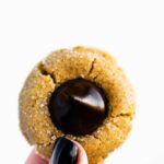 two fingers holding a gluten free peanut butter blossom cookie