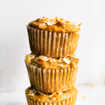 three almond flour banana muffins with coconut stacked on top of each other