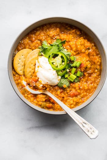 Overhead view of bbq lentil chili with a dollop of sour cream and a couple round crackers on top.