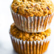 Two gluten free carrot cake muffins in muffin liners stacked on top of each other.