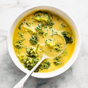 Dairy free broccoli cheese soup in a white bowl with a spoon in it.