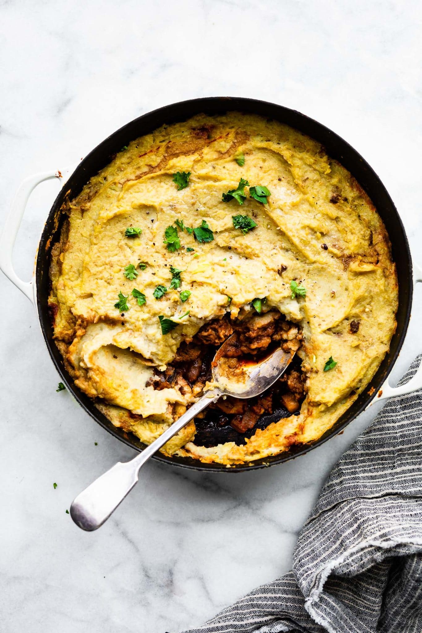 a spoon in a pan full of potato and cauliflower shepherd's pie