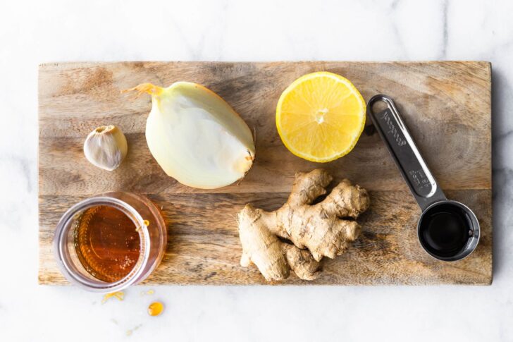 honey, garlic, onion, ginger, lemon, and tamari on a wooden cutting board to make a marinade for honey ginger air fryer chicken