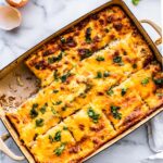 overhead image of a casserole dish with baked tex-mex egg and cauliflower casserole cut into 12 pieces with one piece missing