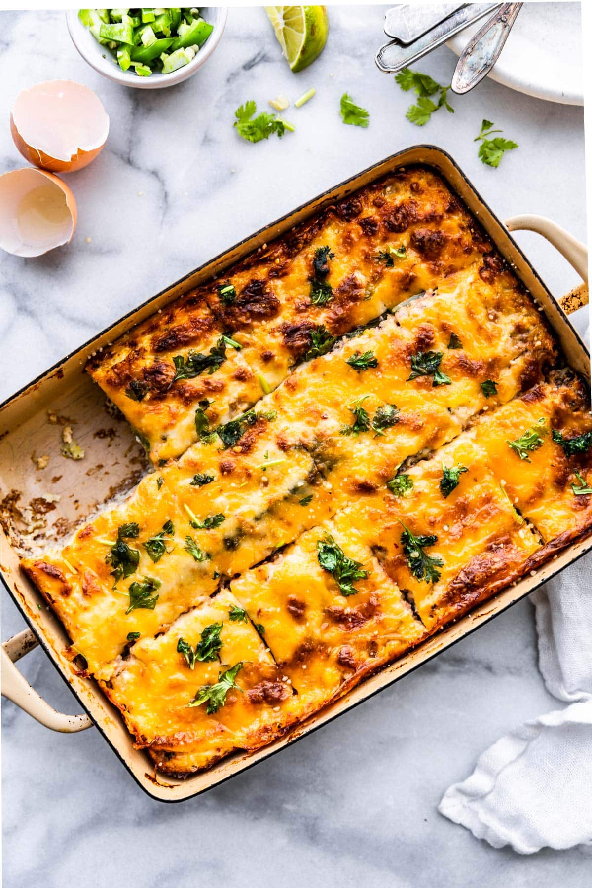 overhead image of a casserole dish with baked tex-mex egg and cauliflower casserole cut into 12 pieces with one piece missing