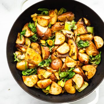 a skillet with roasted leeks and potatoes with onions
