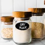 three glass jars full of whole grains the first labeled oat flour