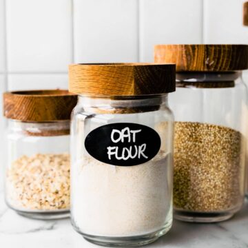 three glass jars full of whole grains the first labeled oat flour