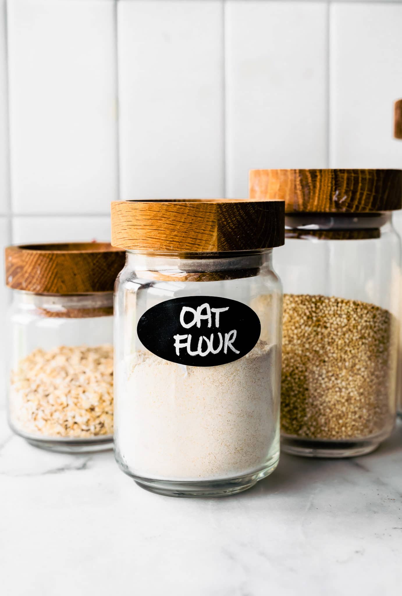 three glass jars full of whole grains the first labeled oat flour
