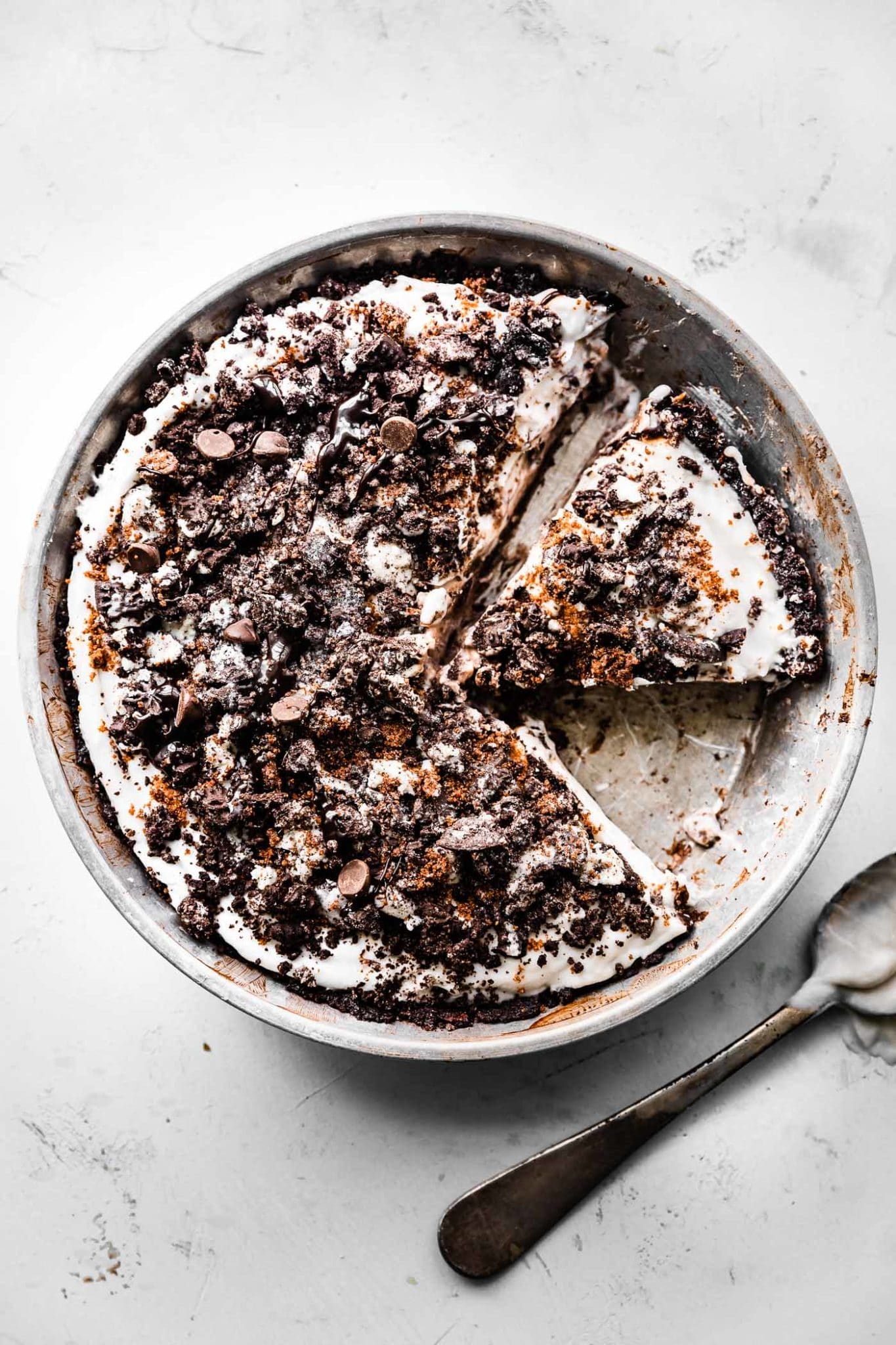 overhead image of vegan dirt pie in a pie tin with a piece missing and another piece sliced and ready to serve