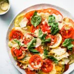 Caesar style tomato salad recipe topped with shaved Parmesan and fresh herbs