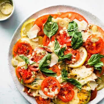 Caesar style tomato salad recipe topped with shaved Parmesan and fresh herbs
