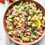 a bowl of strawberry salmon salad topped with a lemon wedge