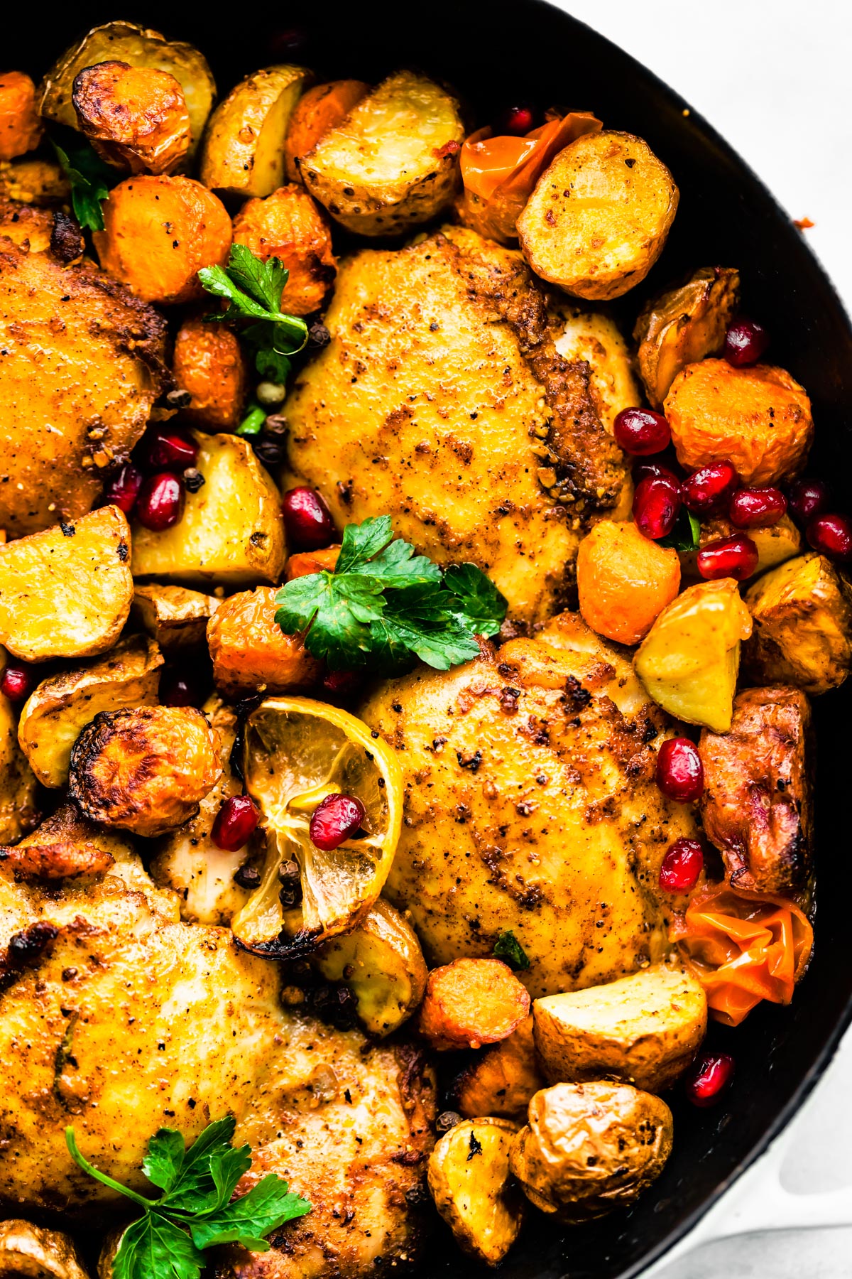 Close-up shot of Persian-Spiced Chicken and Potatoes in a pan garnished with pomegranates