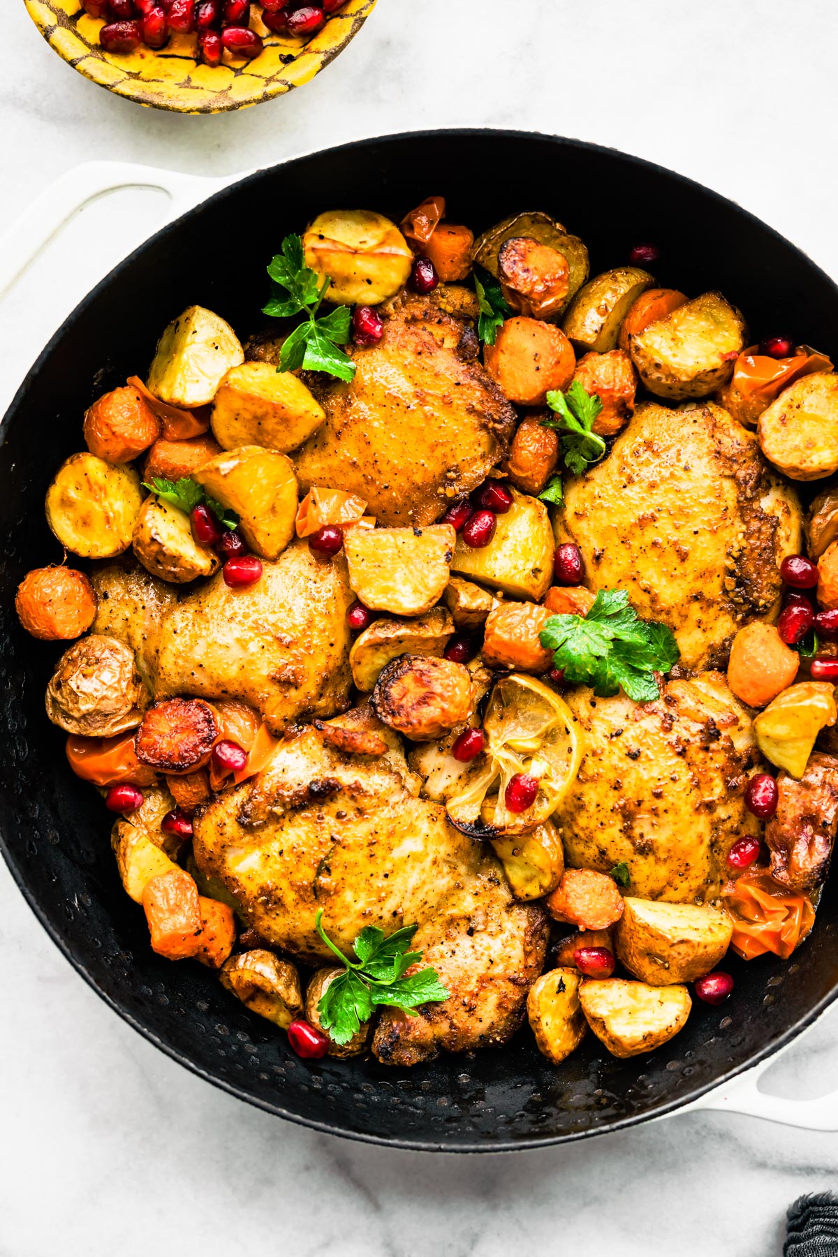 Overhead shot of Persian-Spiced Chicken and Potatoes  in a pan garnished with pomegranates 