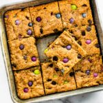 Overhead image of a pan of gluten free monster cookie bars with one removed and placed on top.