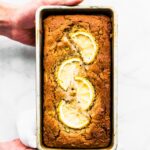 Two hands holding a baked loaf of lemon zucchini bread.