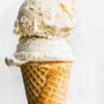 No churn fruit ice cream on top of a sugar cone against a white background.