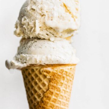 No churn fruit ice cream on top of a sugar cone against a white background.