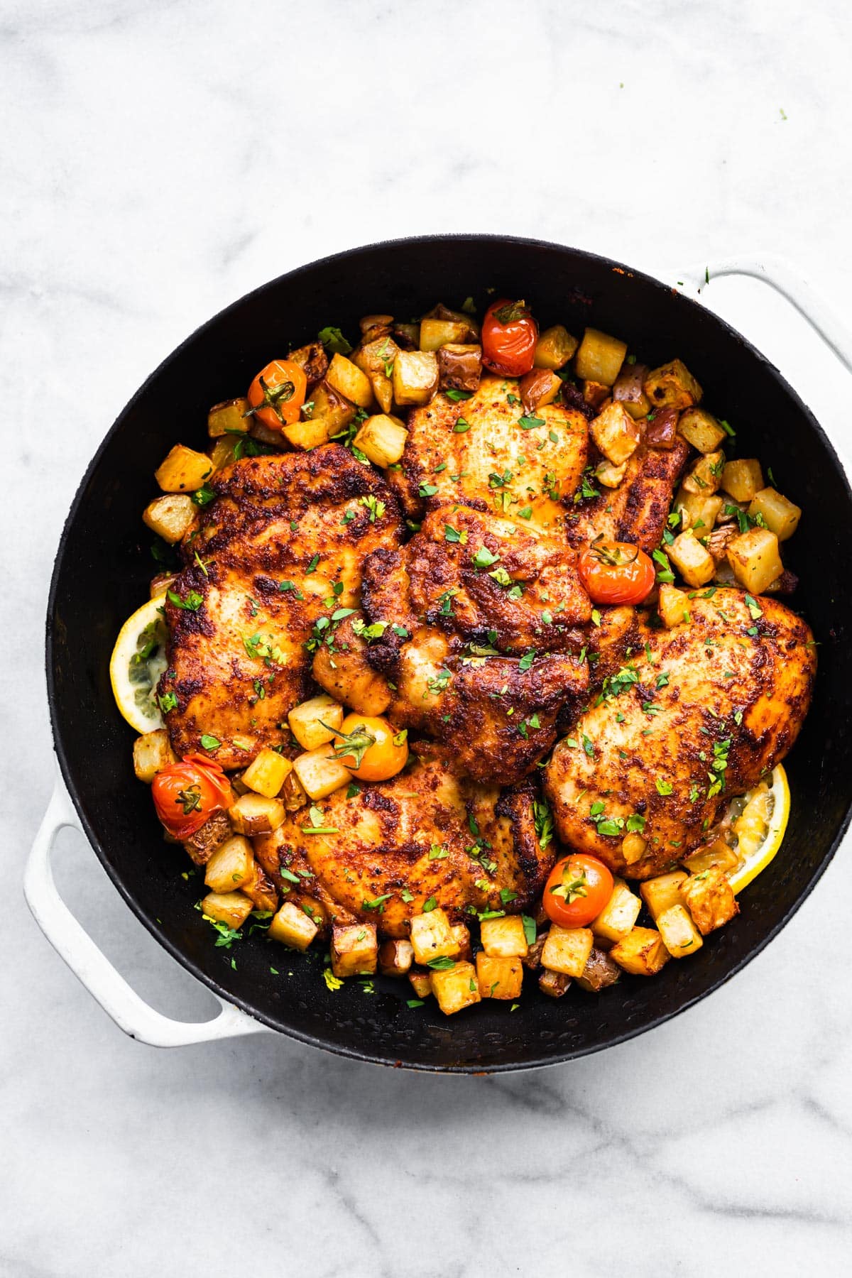 Overhead photo of gluten free paprika chicken thighs surrounded by diced veggies in a pan.