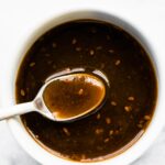 An overhead photo of a spoonful of gluten free teriyaki sauce over a white bowl.