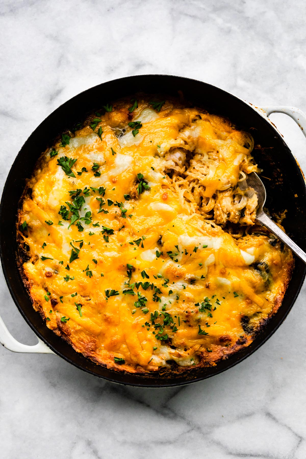 A cheesy spaghetti squash casserole with a spoon in it.