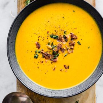 Overhead photo of a bowl of butternut squash soup and a spoon on the side.
