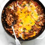 A spoon in a gluten free unstuffed bell pepper skillet topped with melted cheese.