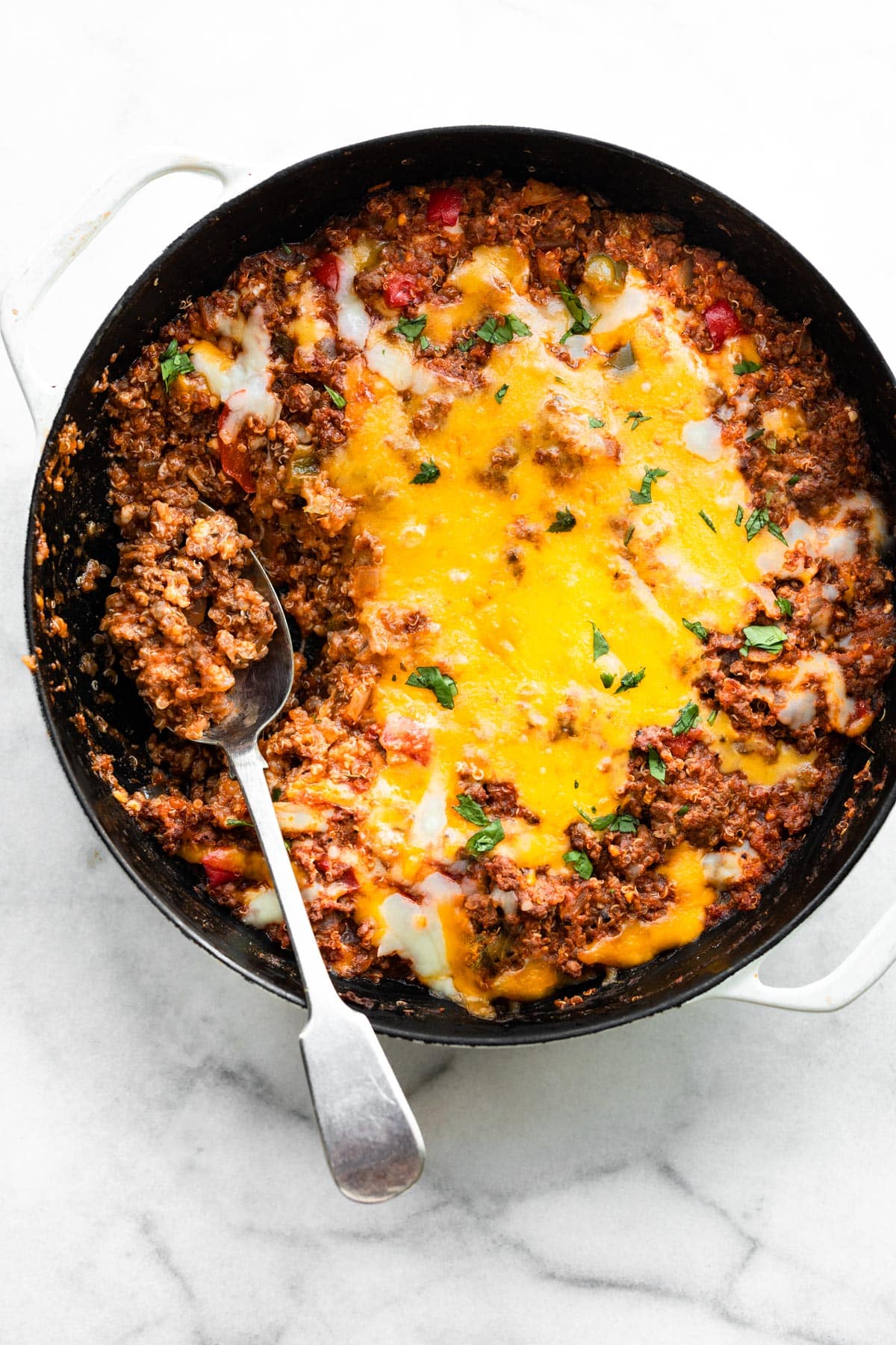 A spoon in a gluten free unstuffed bell pepper skillet topped with melted cheese.
