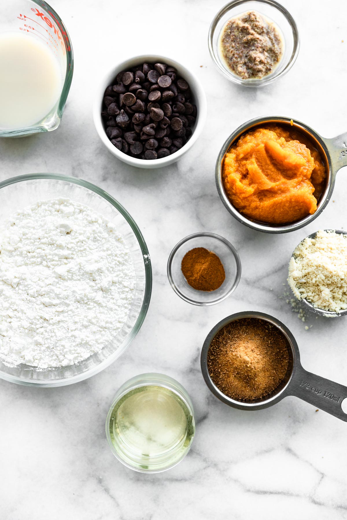 All the ingredients for vegan gluten free pumpkin bread on a white marble countertop.
