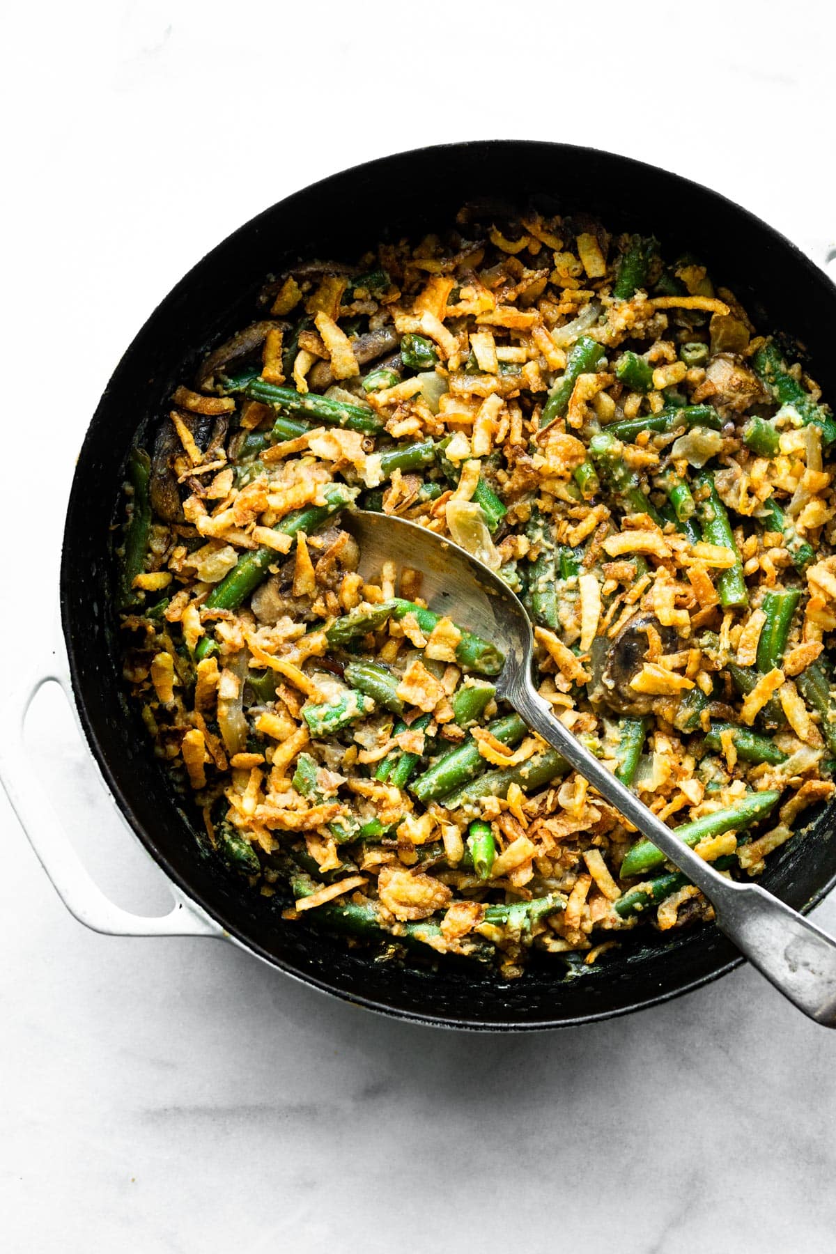 Overhead photo of a pan of vegan green bean casserole with a serving spoon.