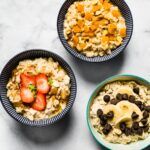 Three bowls of gluten free high protein oatmeal with fresh fruit or chocolate chips.