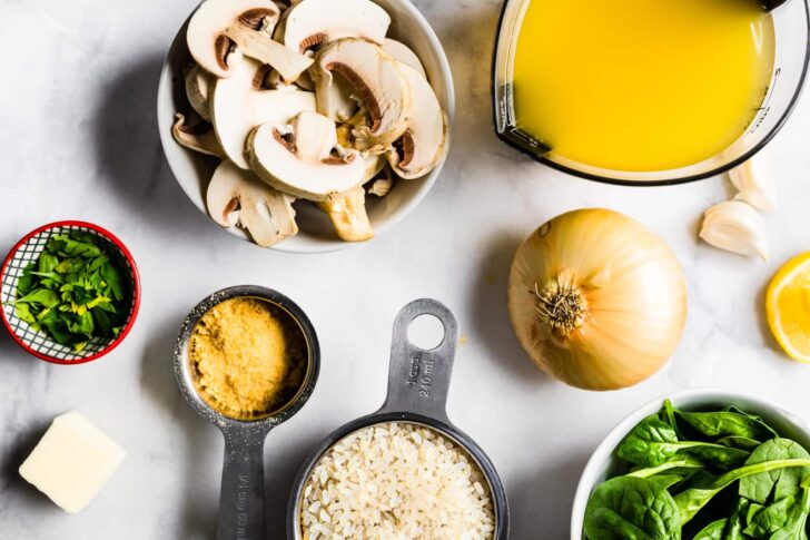 Ingredients for vegan mushroom risotto like vegetable broth, spinach, rice and nutritional yeast.