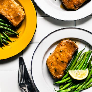 Overhead photo of three plates of glazed pork chops with a side of green beans.