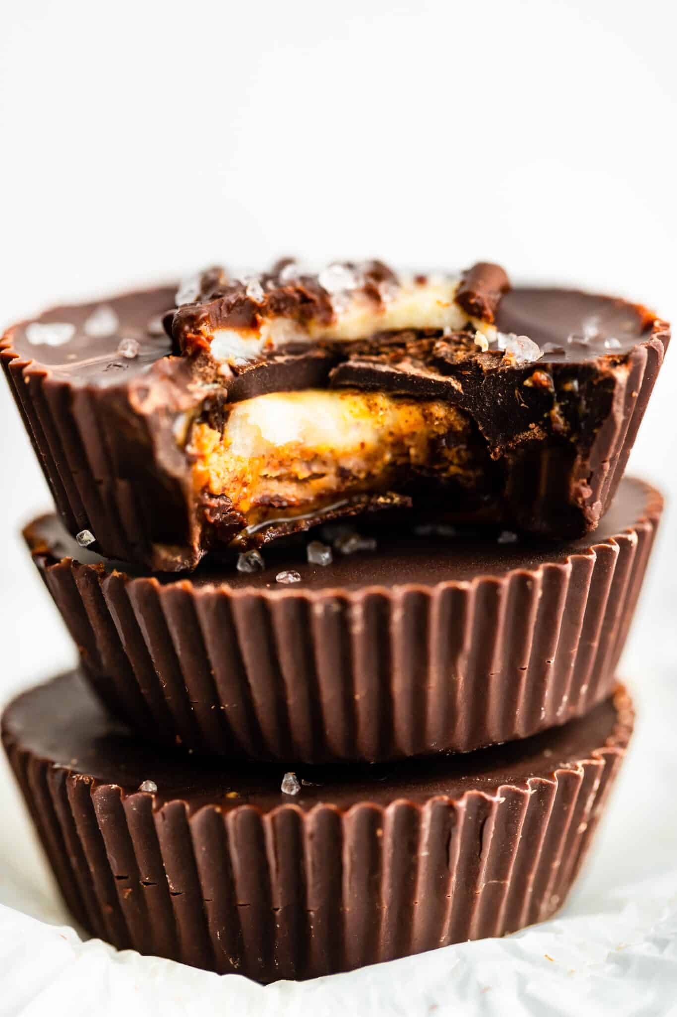 A stack of three chocolate almond butter cups with banana and a bite taken out.