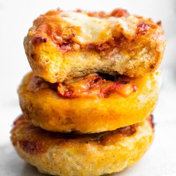 A stack of three pizza muffins with a bite taken out of the top muffin.