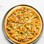 Overhead photo of a gluten free BBQ chicken pizza topped with green onions.