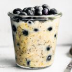jar of blueberry overnight oatmeal with spoon on the side and blueberries on top