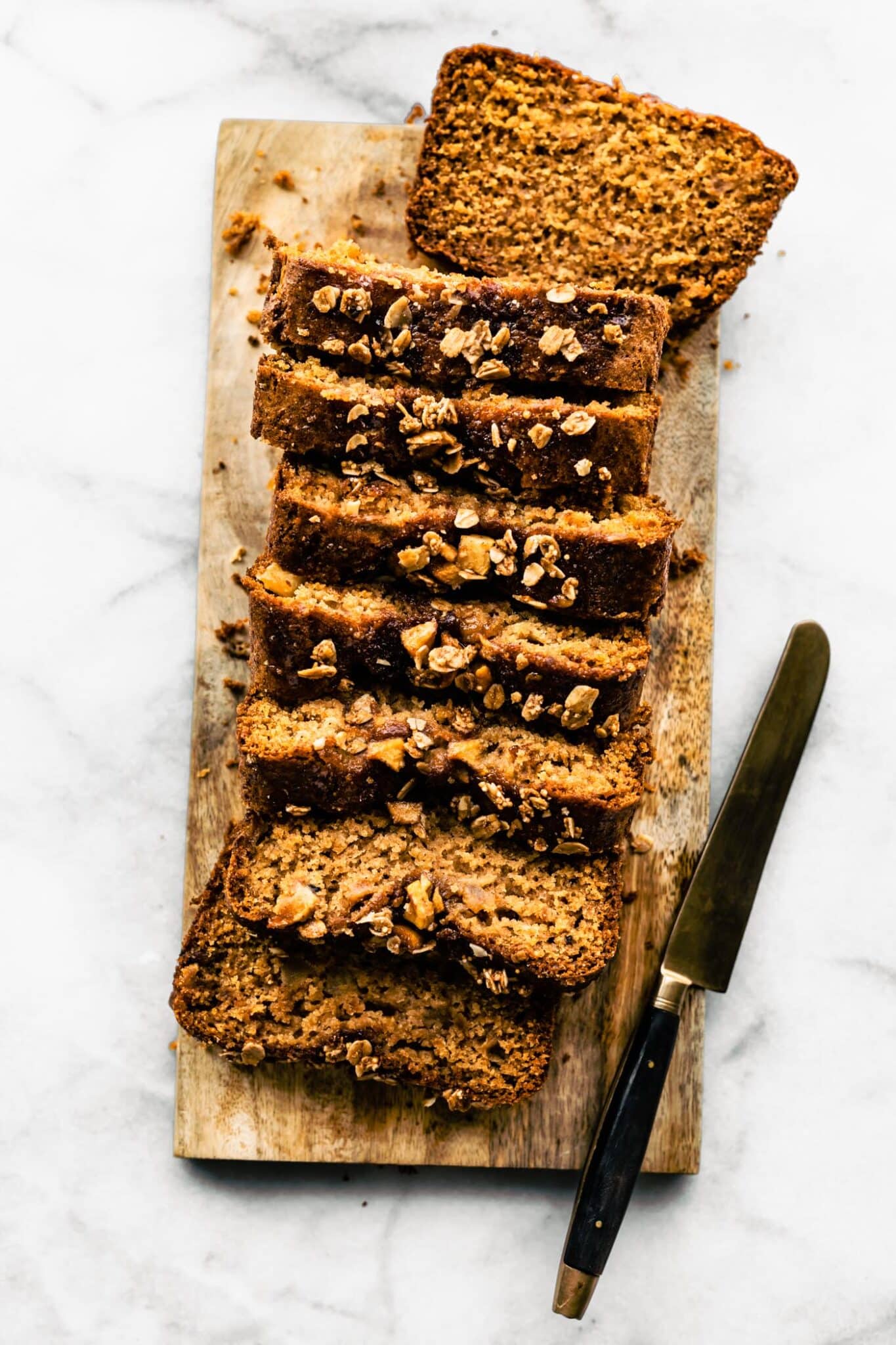 Sliced gluten free apple bread on a wooden cutting board with a knife.