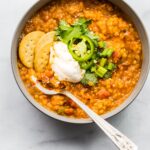 Overhead photo of a bowl of crockpot bbq lentil chili with toppings.