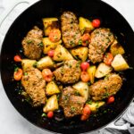 Overhead photo of cooked Mediterranean pork medallions with potatoes and tomatoes.
