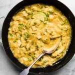 Overhead photo of a spoon in a pan of saucy coconut milk chicken.