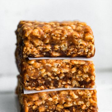 A stack of three homemade protein bars with wax paper between them.